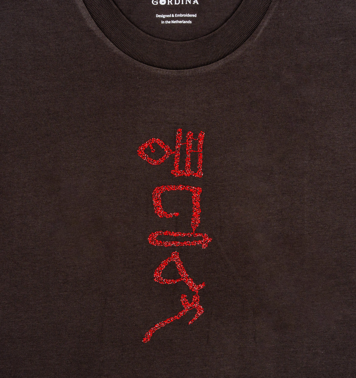 Close-up of hieroglyphic-style embroidery on The Papyrus coal T-shirt.