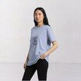 Load image into Gallery viewer, Model wearing the La Bailarina powder T-shirt with a burgundy-thread dancing figure embroidered at the centre chest