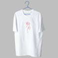 Load image into Gallery viewer, A white t-shirt on a blue wire hanger against a light grey background. It features a small, abstract embroidered design on the center chest consisting of a continuous, minimalist red line that forms the shape of an eye and nose profile.