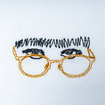 Load image into Gallery viewer, Close-up of white organic cotton t-shirt with embroidered glasses and fringe detail, Gordina