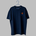 Load image into Gallery viewer, A navy blue t-shirt on a blue wire hanger against a light grey background. It features a small embroidered design on the left chest depicting the blue outline of a person's shoulders and neck, with a tangled orange scribble where the head should be.