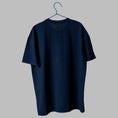Load image into Gallery viewer, The back view of a plain navy blue, short-sleeved t-shirt hanging on a blue wire hanger against a light grey background.
