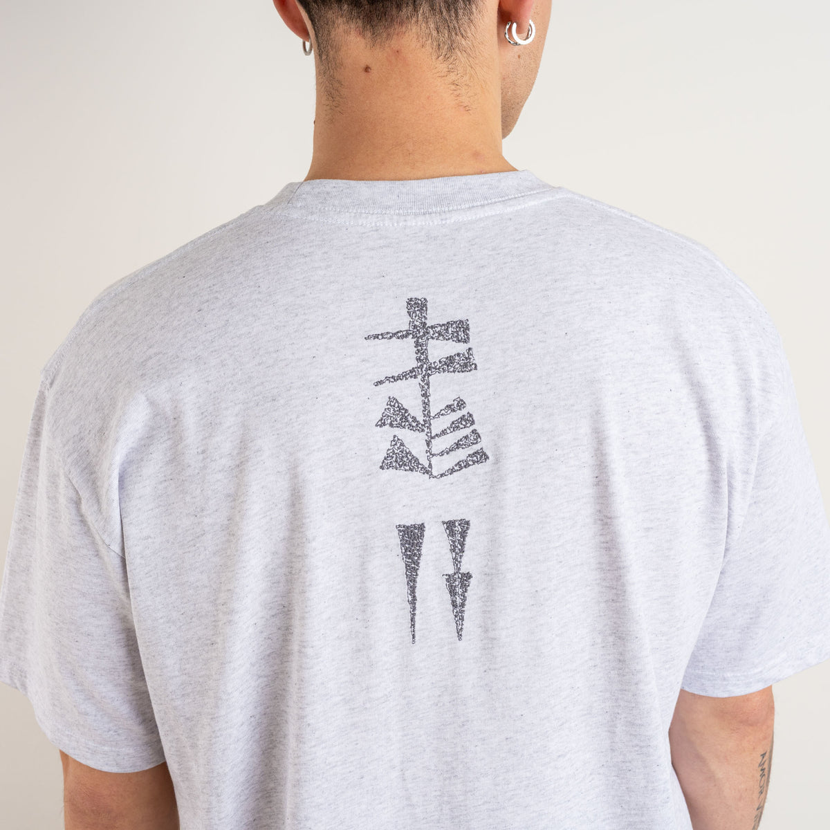 Close-up of the charcoal Garden and Water cuneiform-inspired embroidery on the back of a Marble Grey T-shirt.
