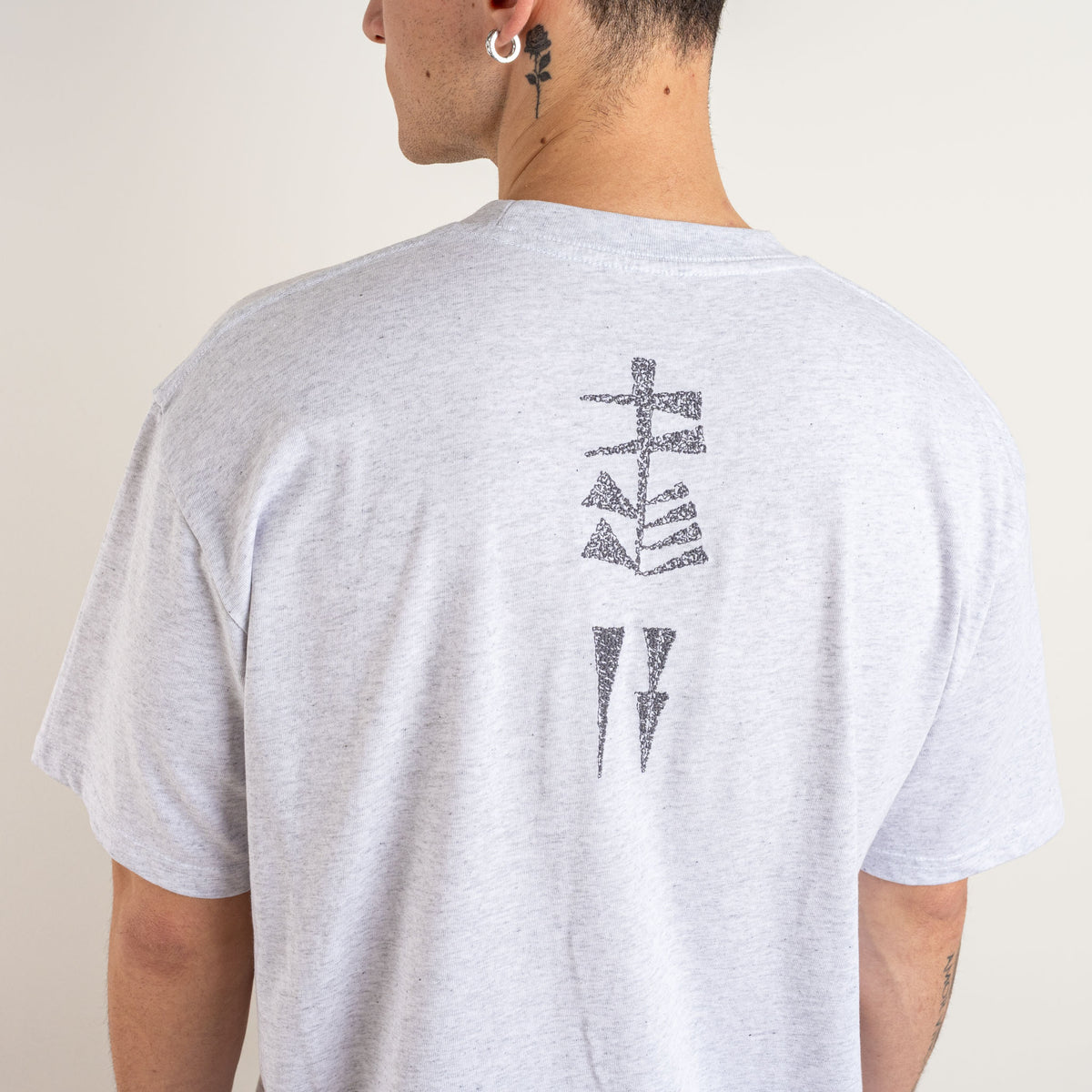 Detailed view of vertical charcoal embroidery on the back of the Gordina Marble Grey Garden and Water T-shirt.