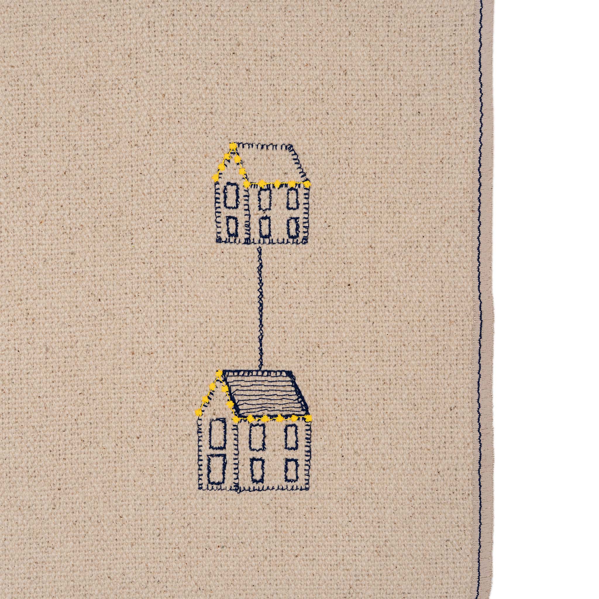 Set of four embroidered cotton placemats with connected house motifs, celebrating family, home, and craftsmanship.
