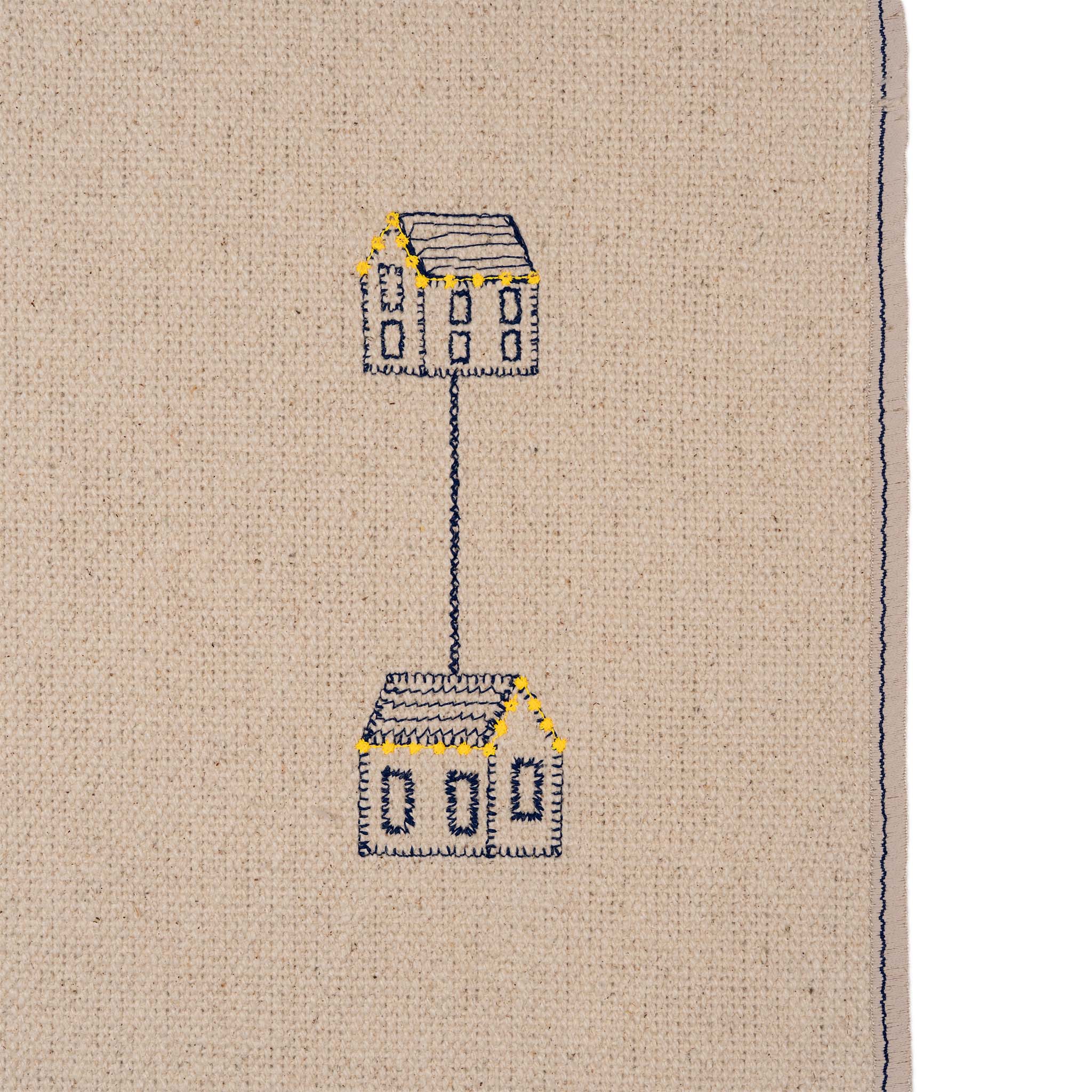 Set of four embroidered cotton placemats with connected house motifs, celebrating family, home, and craftsmanship.
