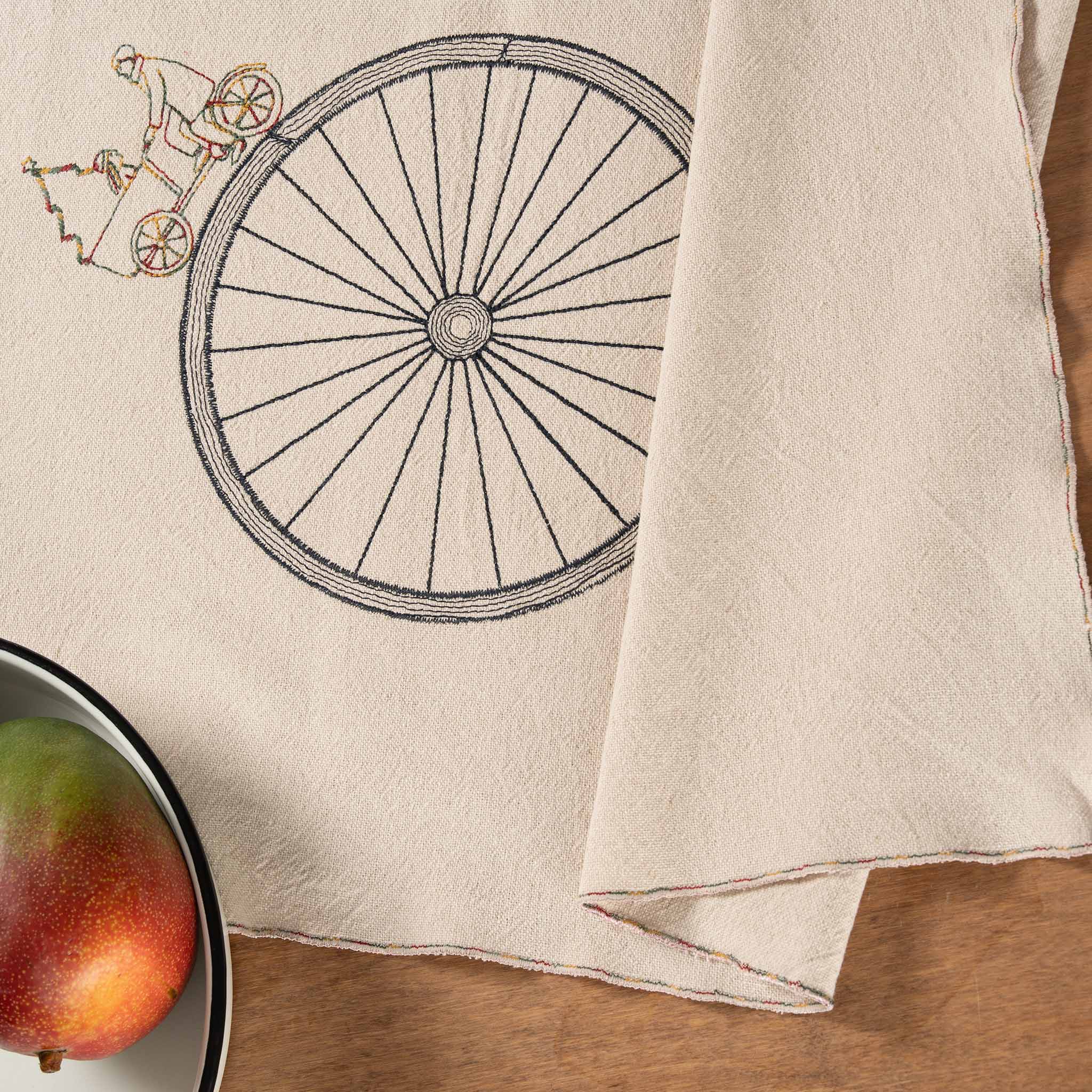Handmade embroidered cotton table runner with bicycle motif, designed in the Netherlands for winter gatherings.
