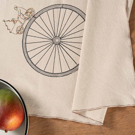 Handmade embroidered cotton table runner with bicycle motif, designed in the Netherlands for winter gatherings.
