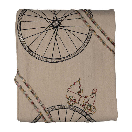 Large embroidered cotton tablecloth with bicycle motif, handmade in the Netherlands, celebrating movement and connection.
