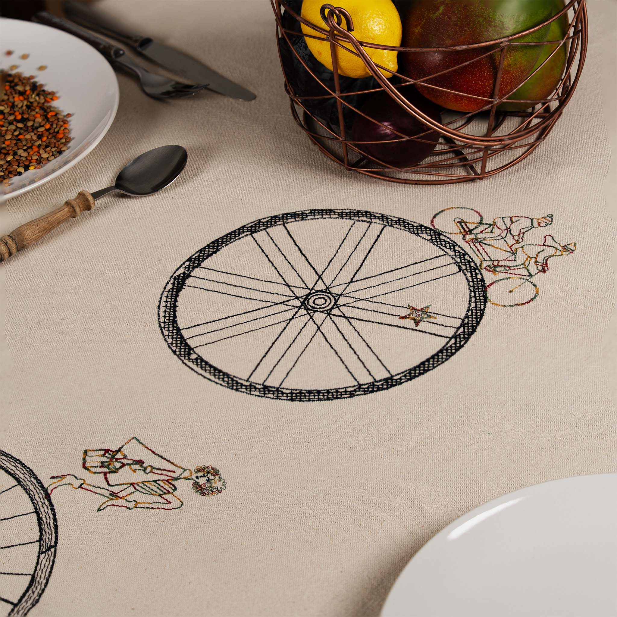 Large embroidered cotton tablecloth with bicycle motif, handmade in the Netherlands, celebrating movement and connection.
