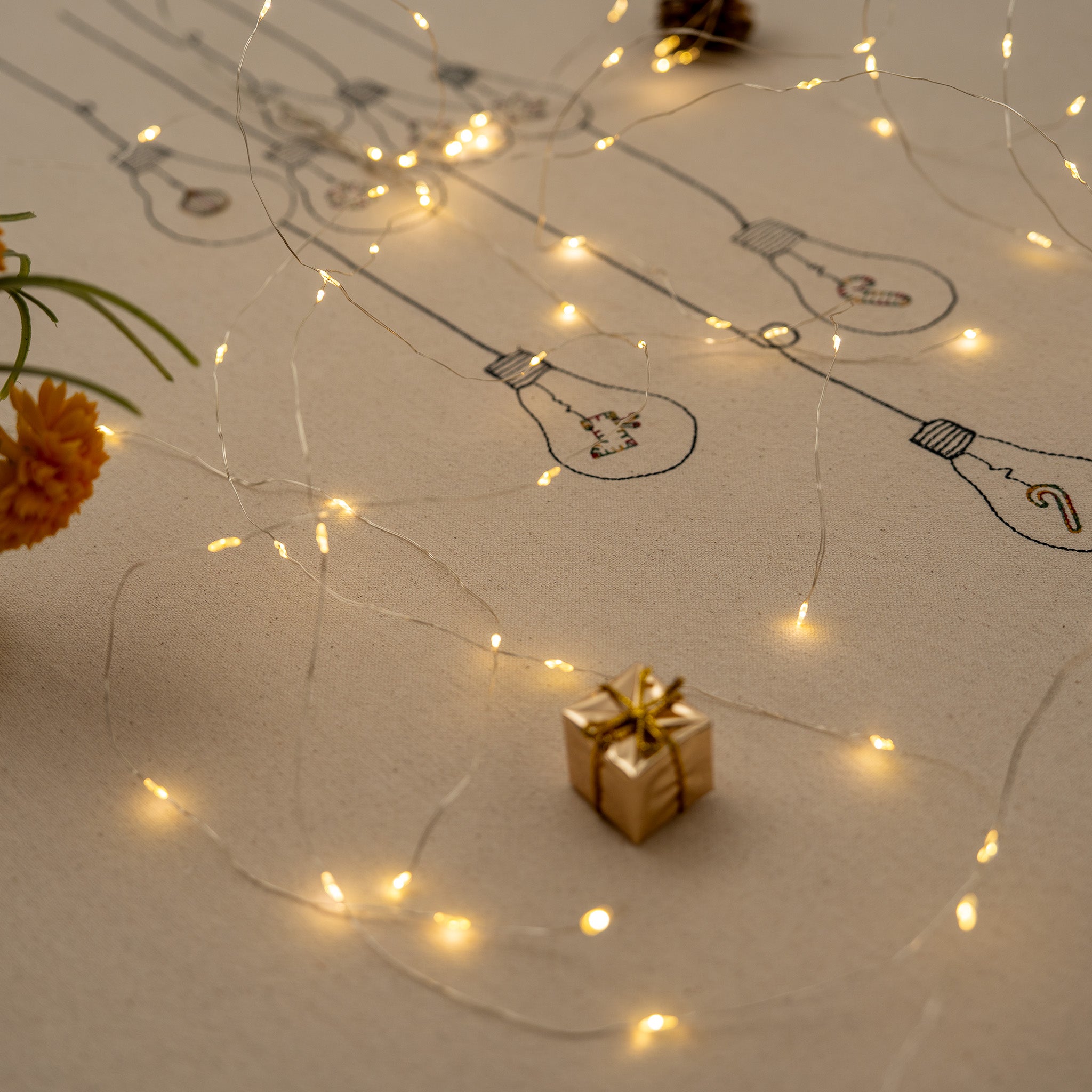 Handmade embroidered cotton tablecloth with festive light bulb design, crafted in the Netherlands for holiday gatherings.
