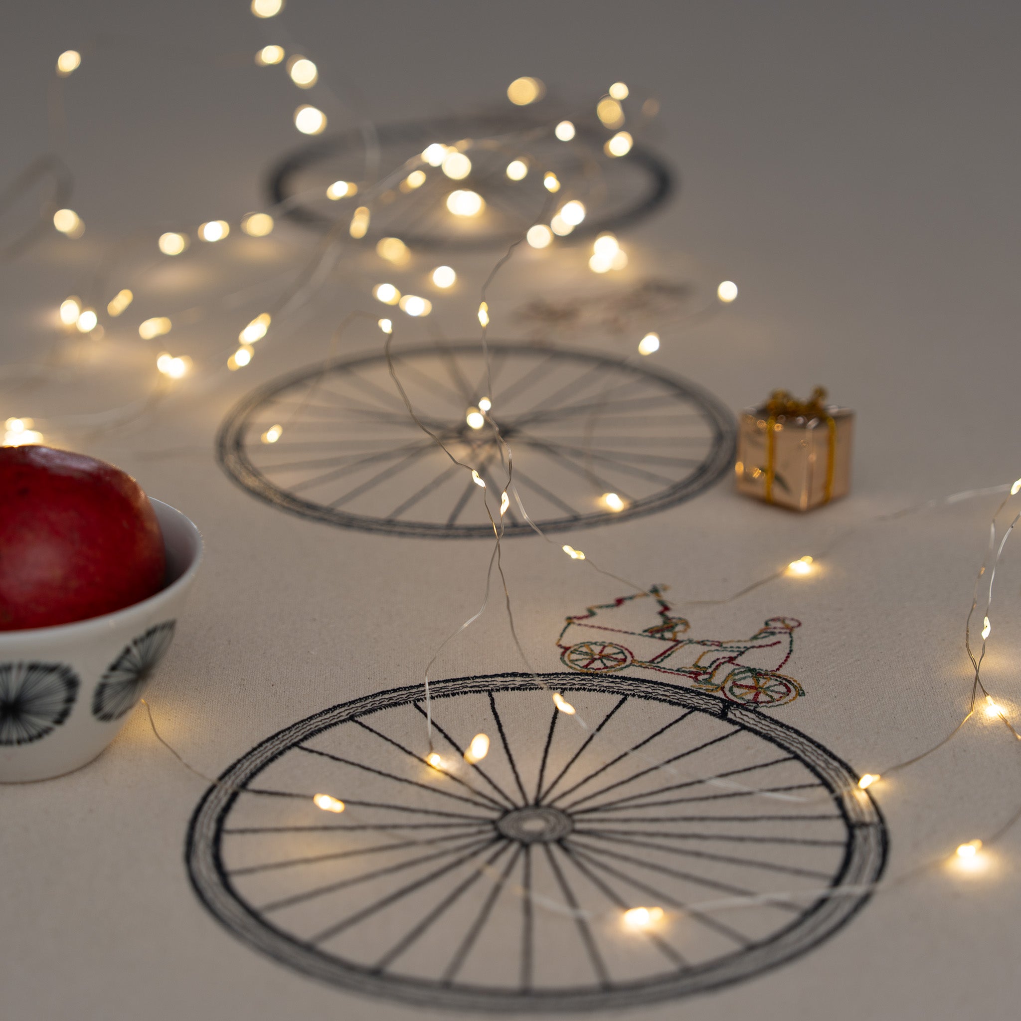 Large embroidered cotton tablecloth with bicycle motif, handmade in the Netherlands, celebrating movement and connection.
