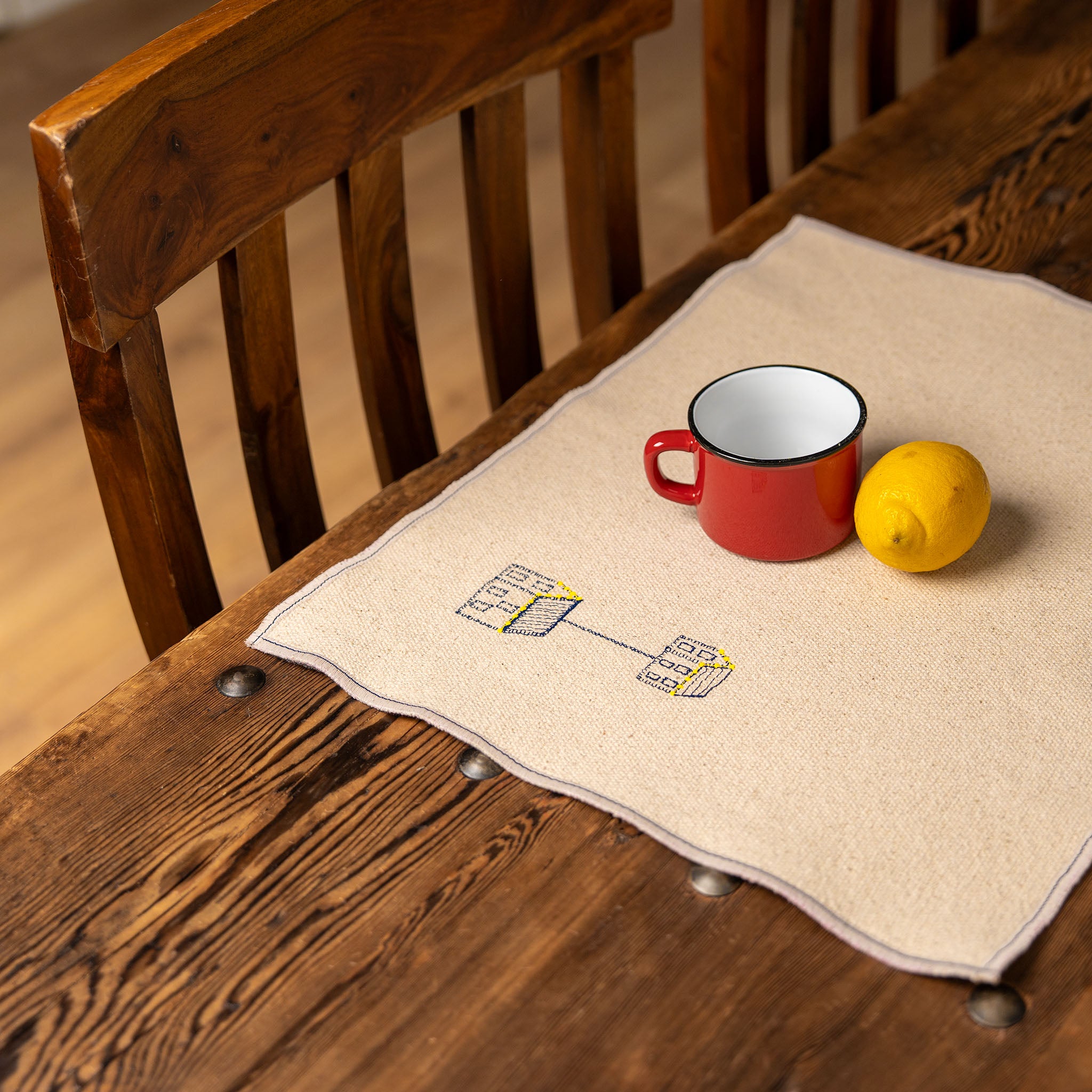Set of four embroidered cotton placemats with connected house motifs, celebrating family, home, and craftsmanship.
