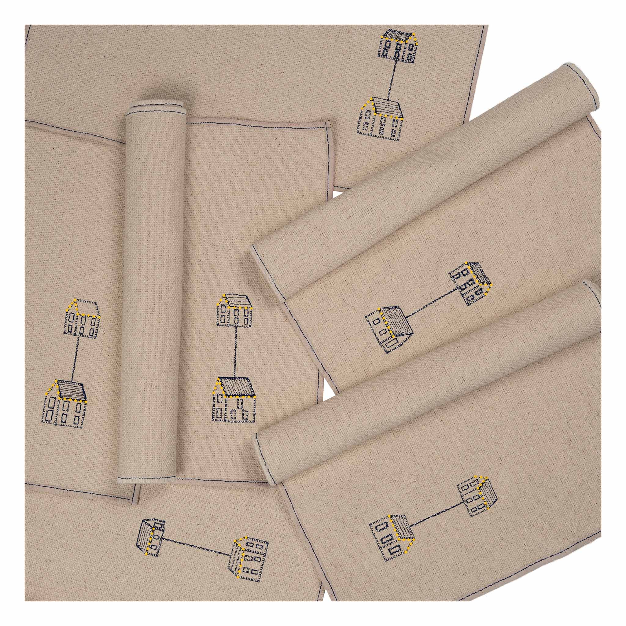 Set of four embroidered cotton placemats with connected house motifs, celebrating family, home, and craftsmanship.
