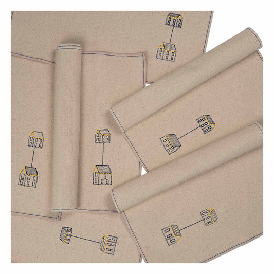 Set of four embroidered cotton placemats with connected house motifs, celebrating family, home, and craftsmanship.
