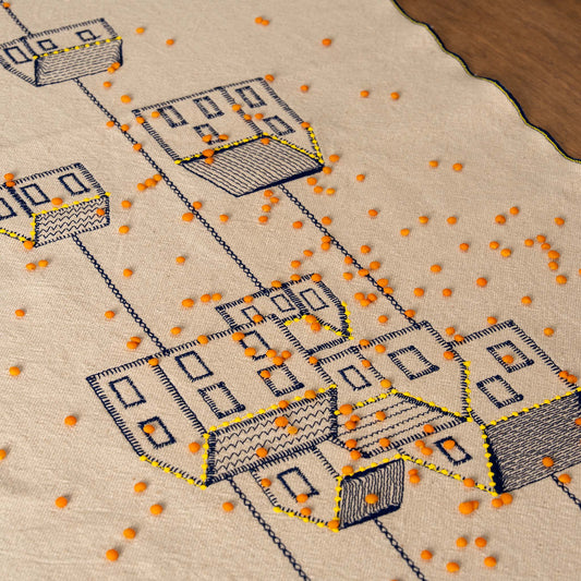 Embroidered cotton table runner featuring connected houses design, symbolizing home, family, and belonging.
