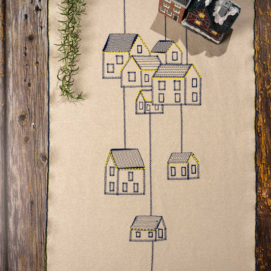 Embroidered cotton table runner featuring connected houses design, symbolizing home, family, and belonging.

