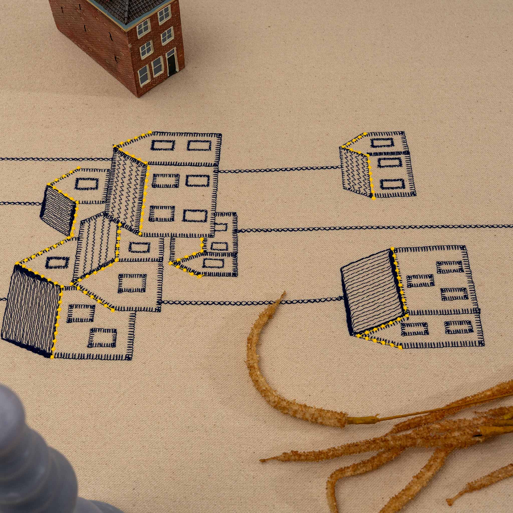 Handmade embroidered cotton tablecloth featuring connected houses, designed to evoke warmth and togetherness.
