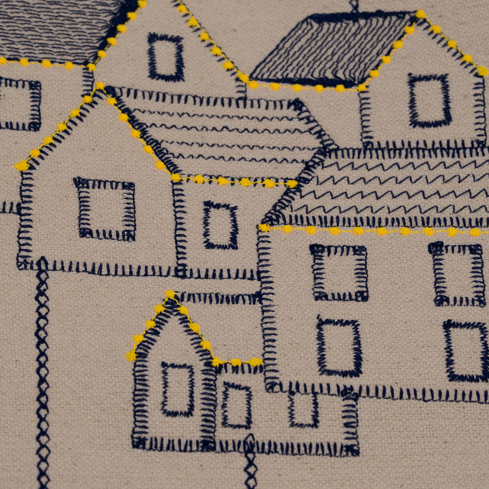 Handmade embroidered cotton tablecloth featuring connected houses, designed to evoke warmth and togetherness.
