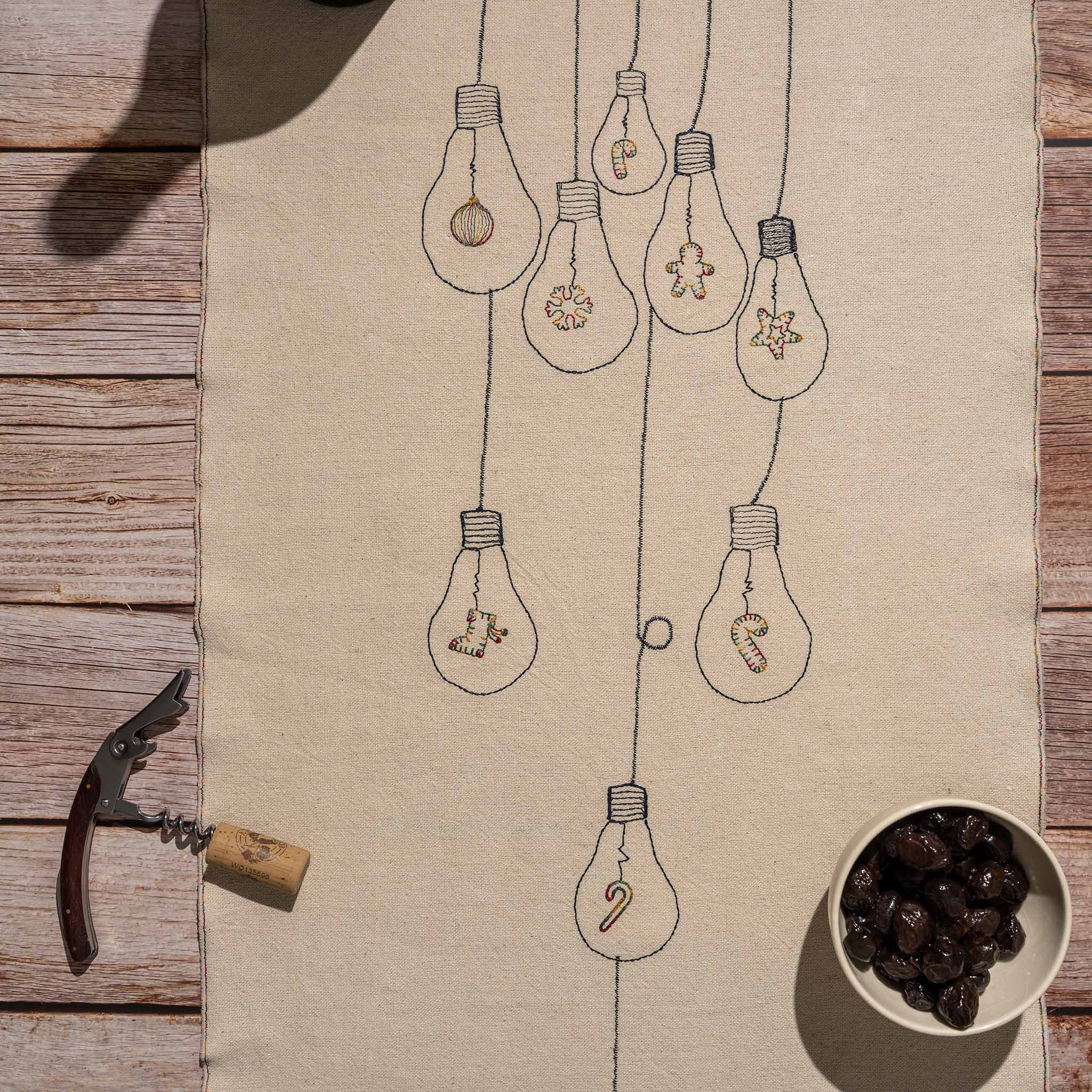 Handcrafted embroidered cotton table runner with light bulb pattern, inspired by festive traditions and glowing memories.
