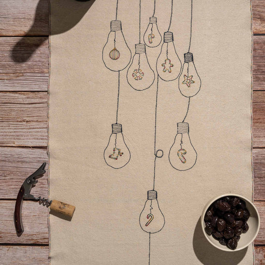 Handcrafted embroidered cotton table runner with light bulb pattern, inspired by festive traditions and glowing memories.
