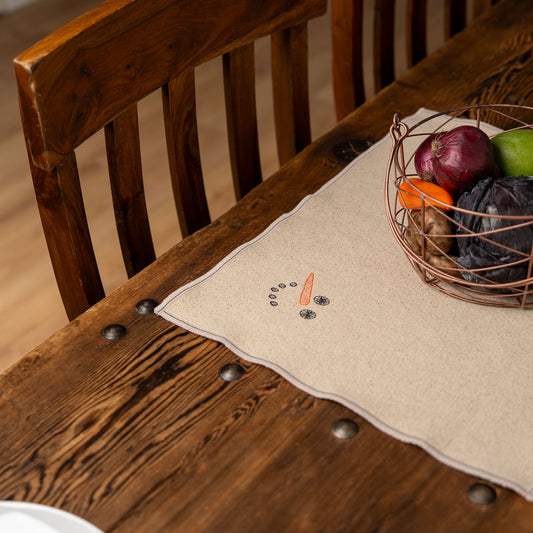 Set of four embroidered cotton placemats with playful snowman design, handmade for winter dining and festive tables.
