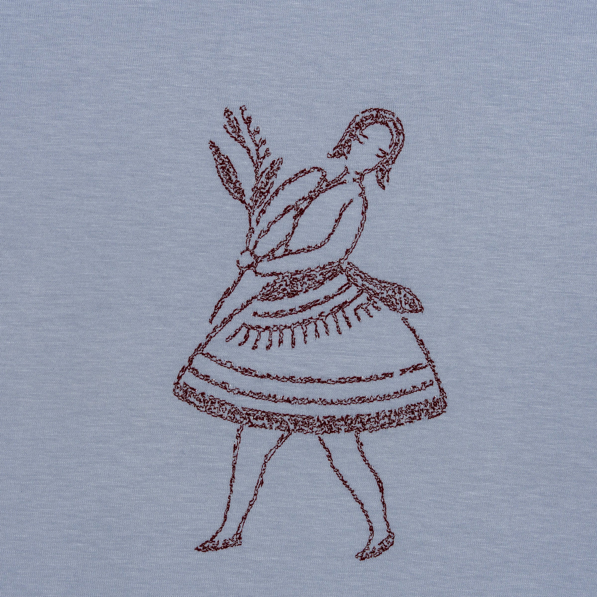 Macro detail of burgundy-thread embroidery on powder fabric for the La Bailarina dancing-figure motif