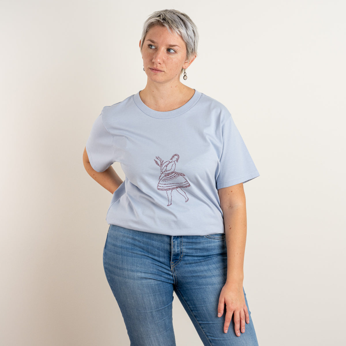 Front view of the La Bailarina Powder women’s T-shirt with a burgundy dancing-figure embroidery by Gordina.