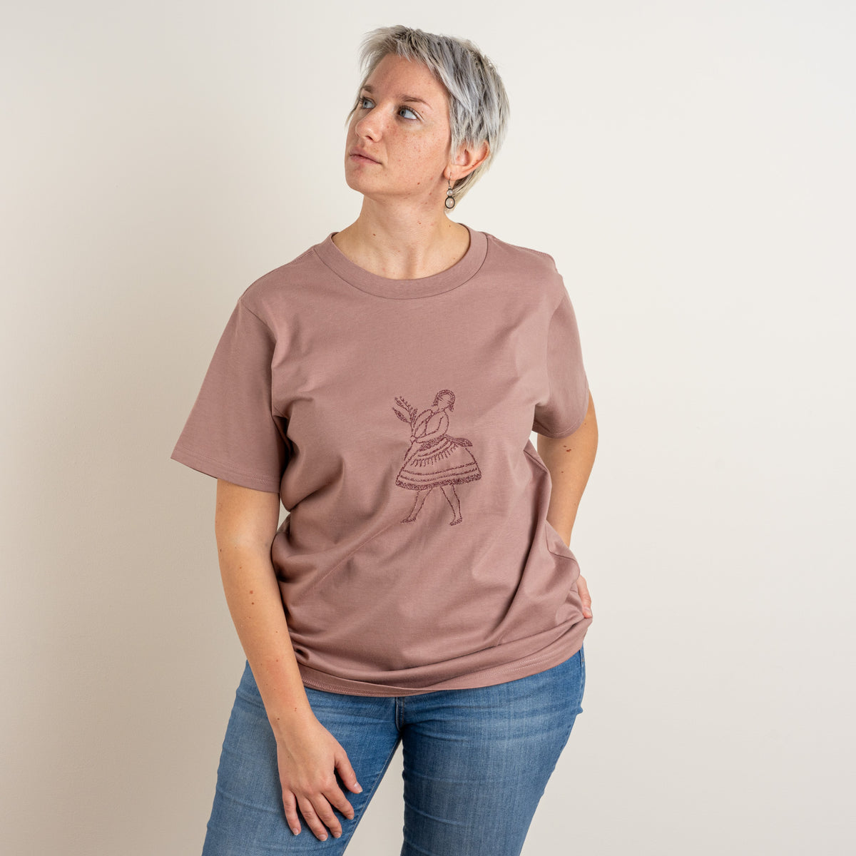 Woman wearing the relaxed Terracotta La Bailarina women’s T-shirt with its dancing-figure embroidery at the centre chest.