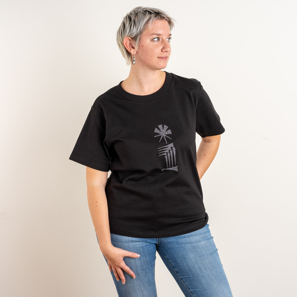 Relaxed angled pose showing the women’s black Star and House embroidered T-shirt.