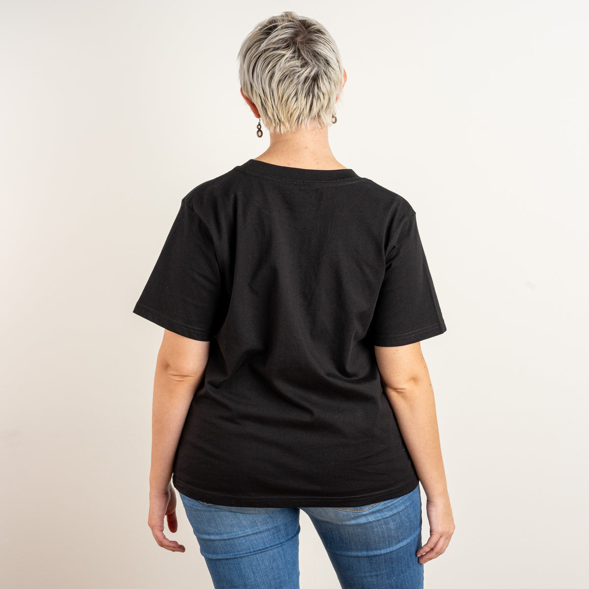 Side-facing model wearing the women’s black Star and House T-shirt with embroidered chest design.