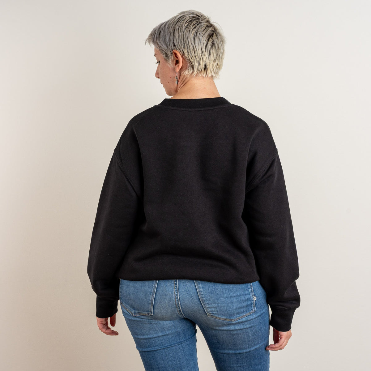Back view of the black personalised Women’s Relaxed Sweatshirt on a model, ready for upper-back embroidery