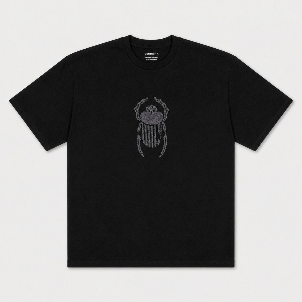 Flat lay of the Gordina The Scarab black oversized T-shirt with grey scarab embroidery.