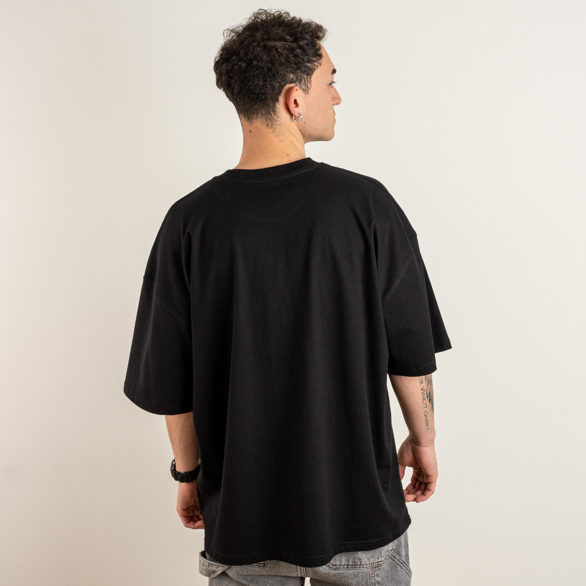 Side-angled model view of the Gordina The Scarab black oversized T-shirt with grey front embroidery.