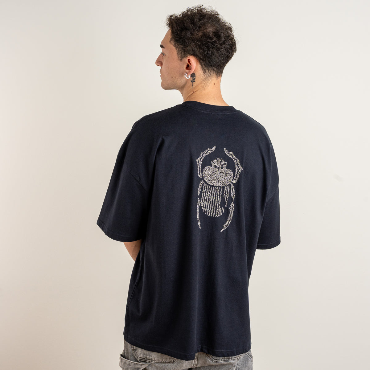 Angled back view of the Gordina The Scarab navy oversized cotton T-shirt with ivory scarab embroidery.