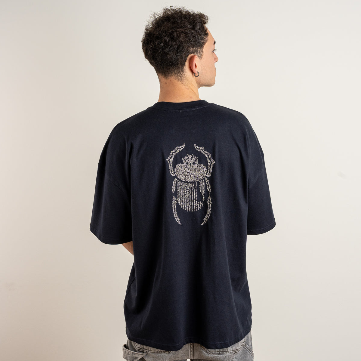 Back view of the Gordina The Scarab navy T-shirt with ivory scarab embroidery, made by a Netherlands embroidery studio.