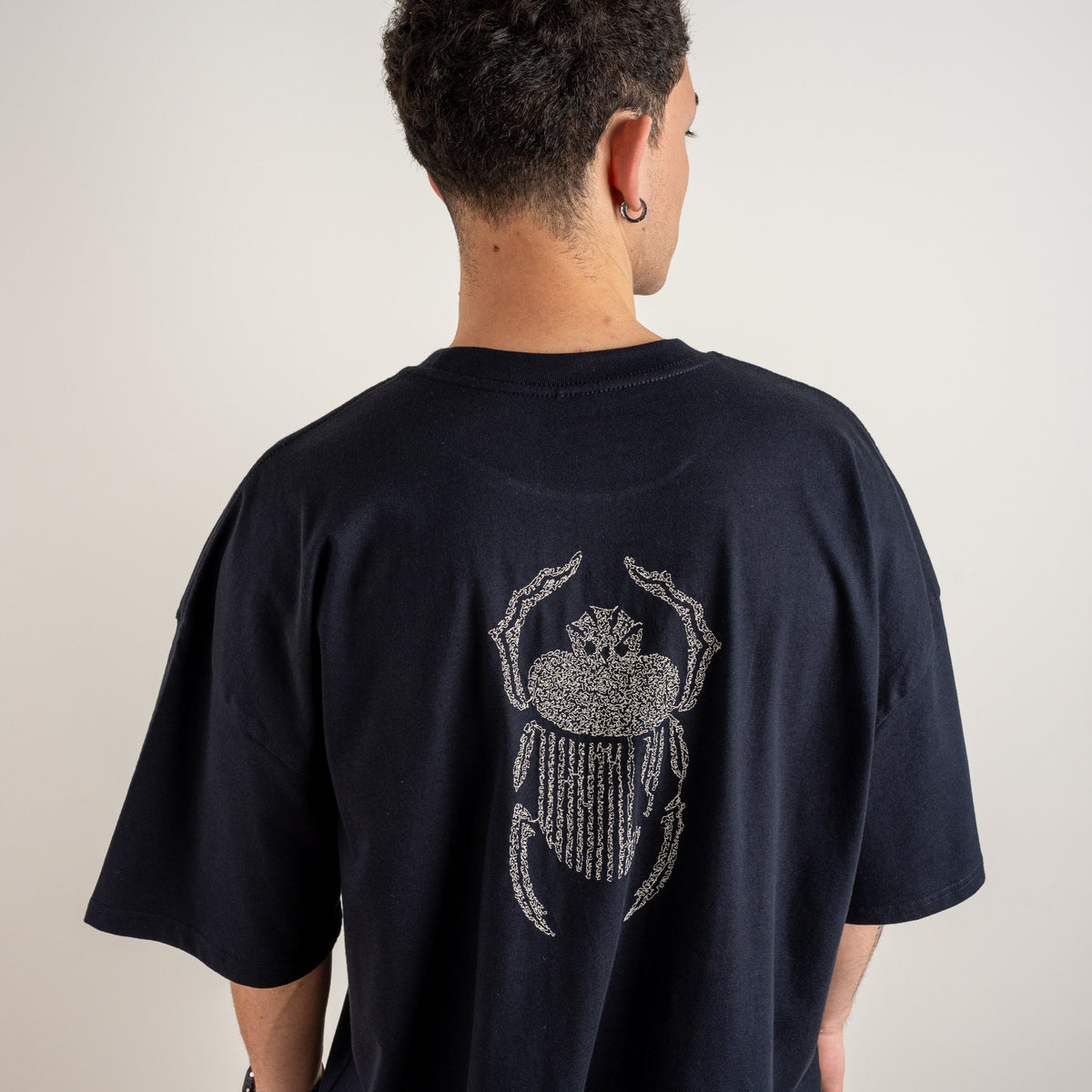 Detailed view of the ivory scarab motif on the back of the Gordina navy heavyweight cotton T-shirt.