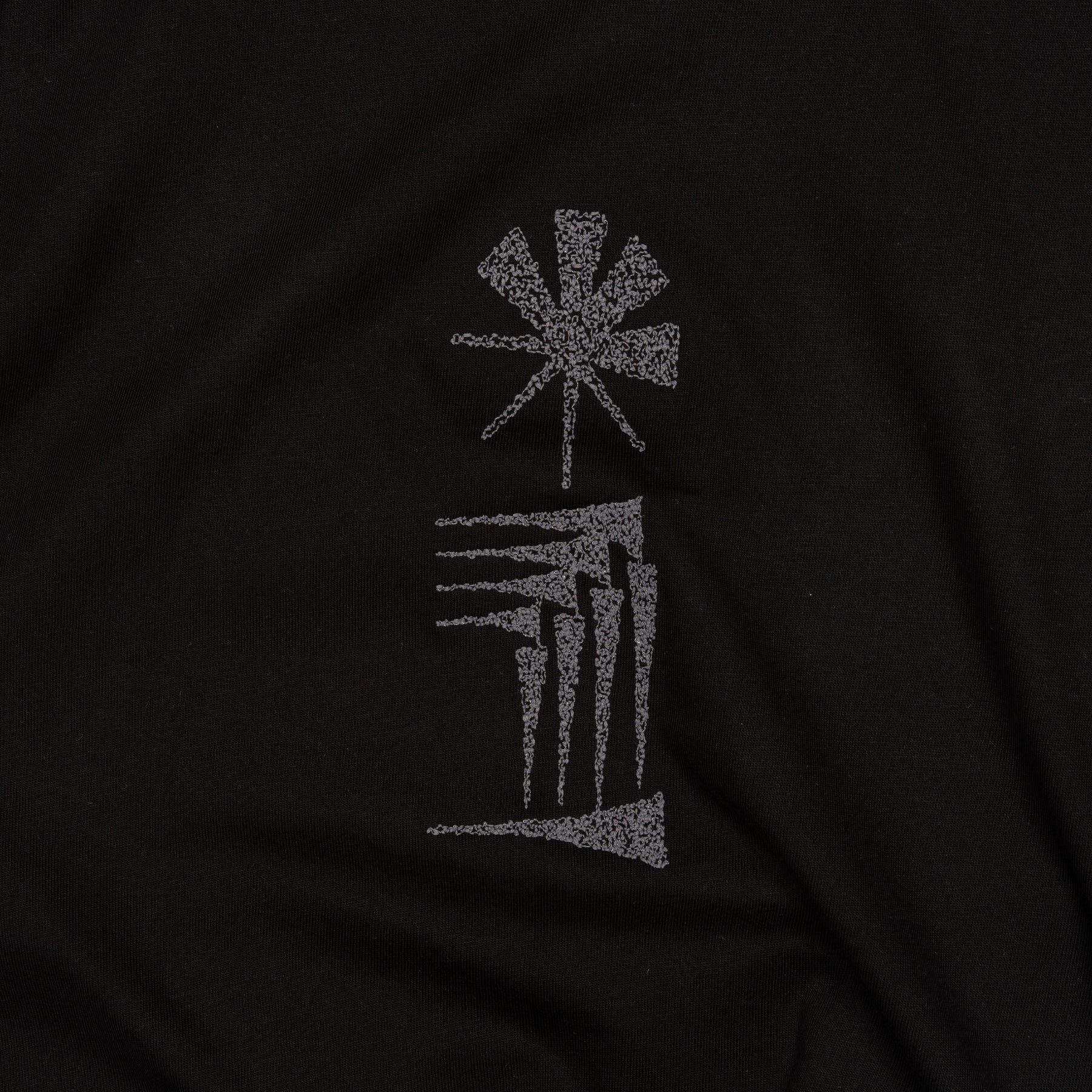 Close-up of the star and house cuneiform embroidery on black cotton