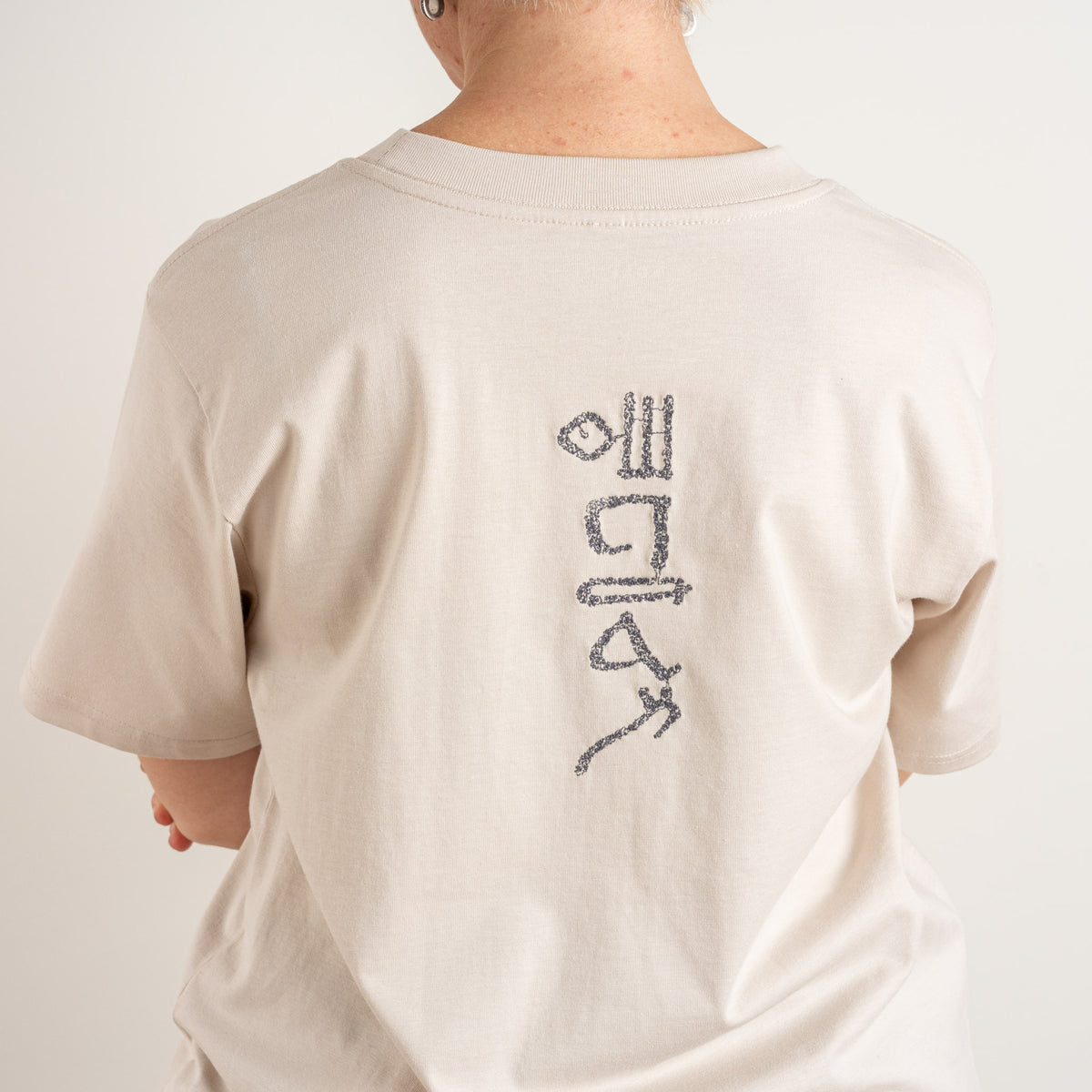 Close-up of the Papyrus hieroglyphic-style embroidery on the Bone T-shirt, stitched in the Netherlands.