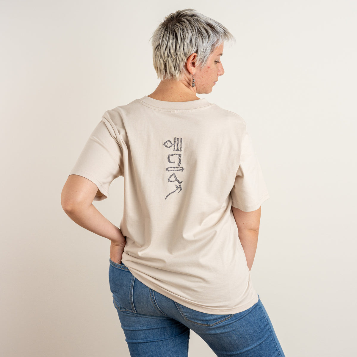 Three-quarter back view of Gordina’s Bone women’s Papyrus T-shirt with its vertical embroidered motif.