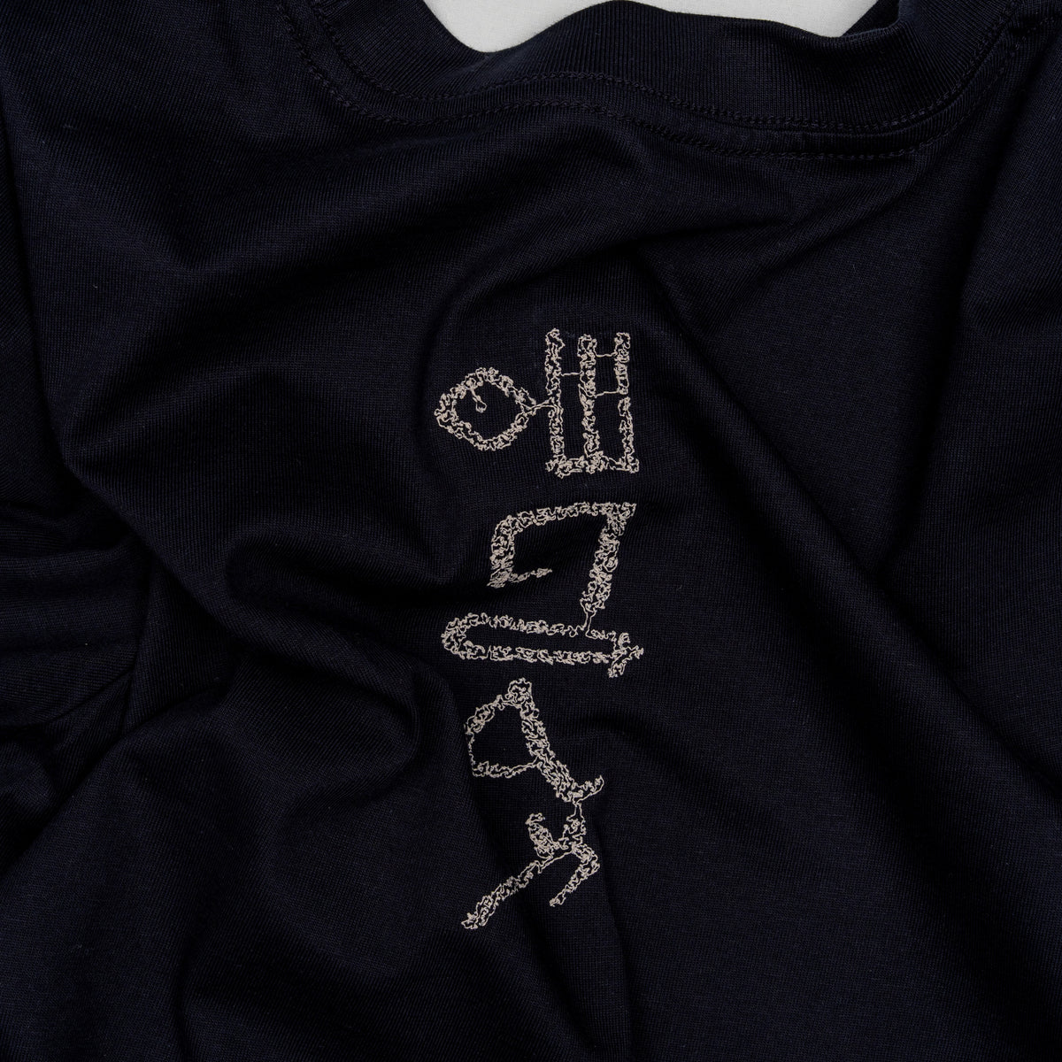 Flat lay of The Papyrus women’s navy T-shirt showing the back motif placement