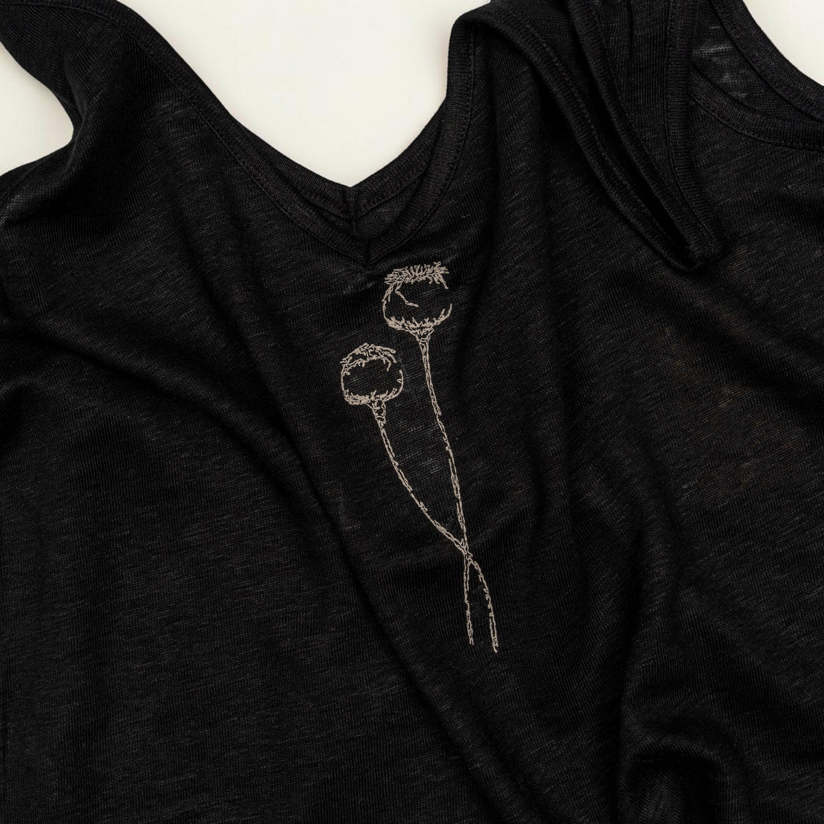 Close-up of cream poppy embroidery on The Poppy Black linen tank top