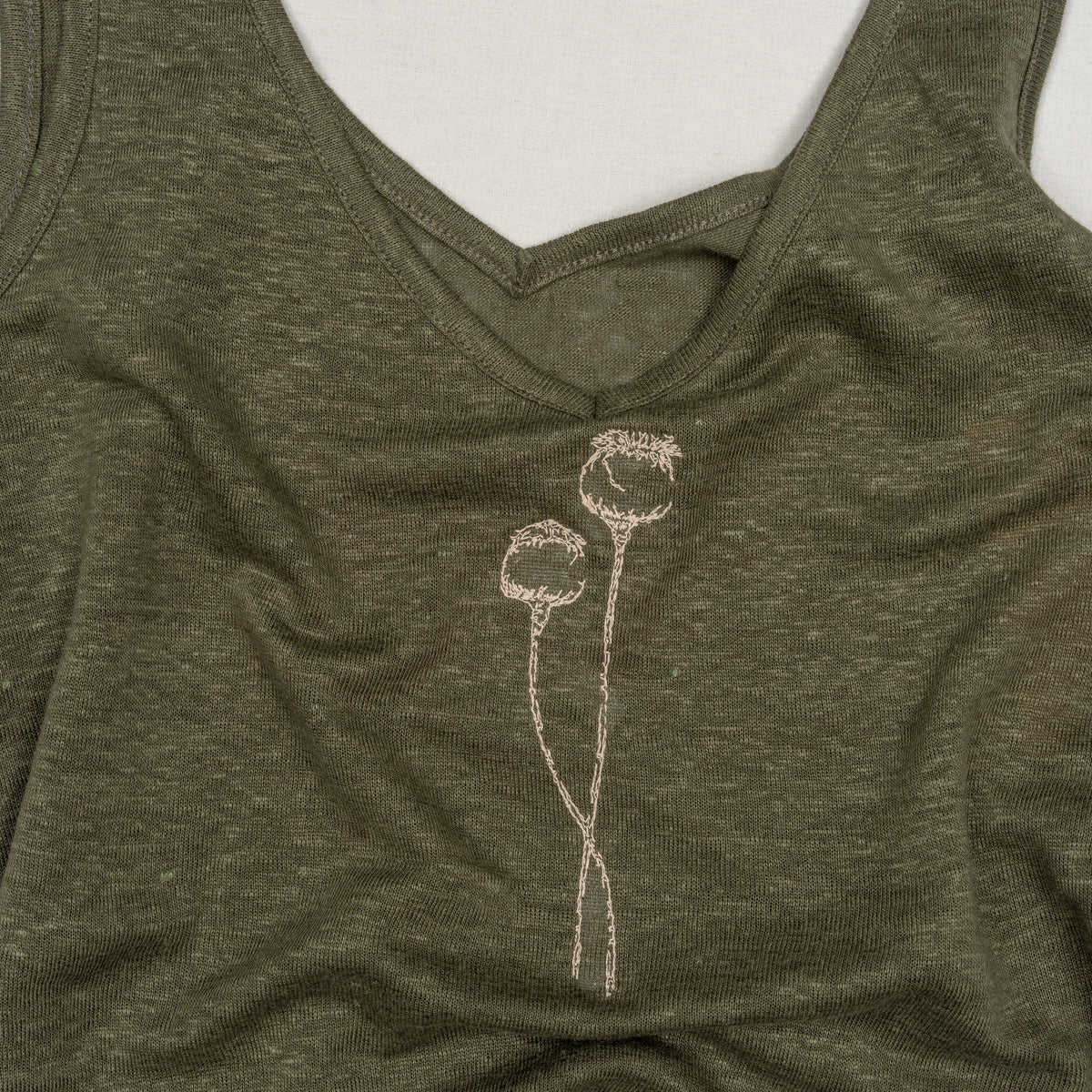 Close-up of cream poppy embroidery on The Poppy Olive Green linen tank top