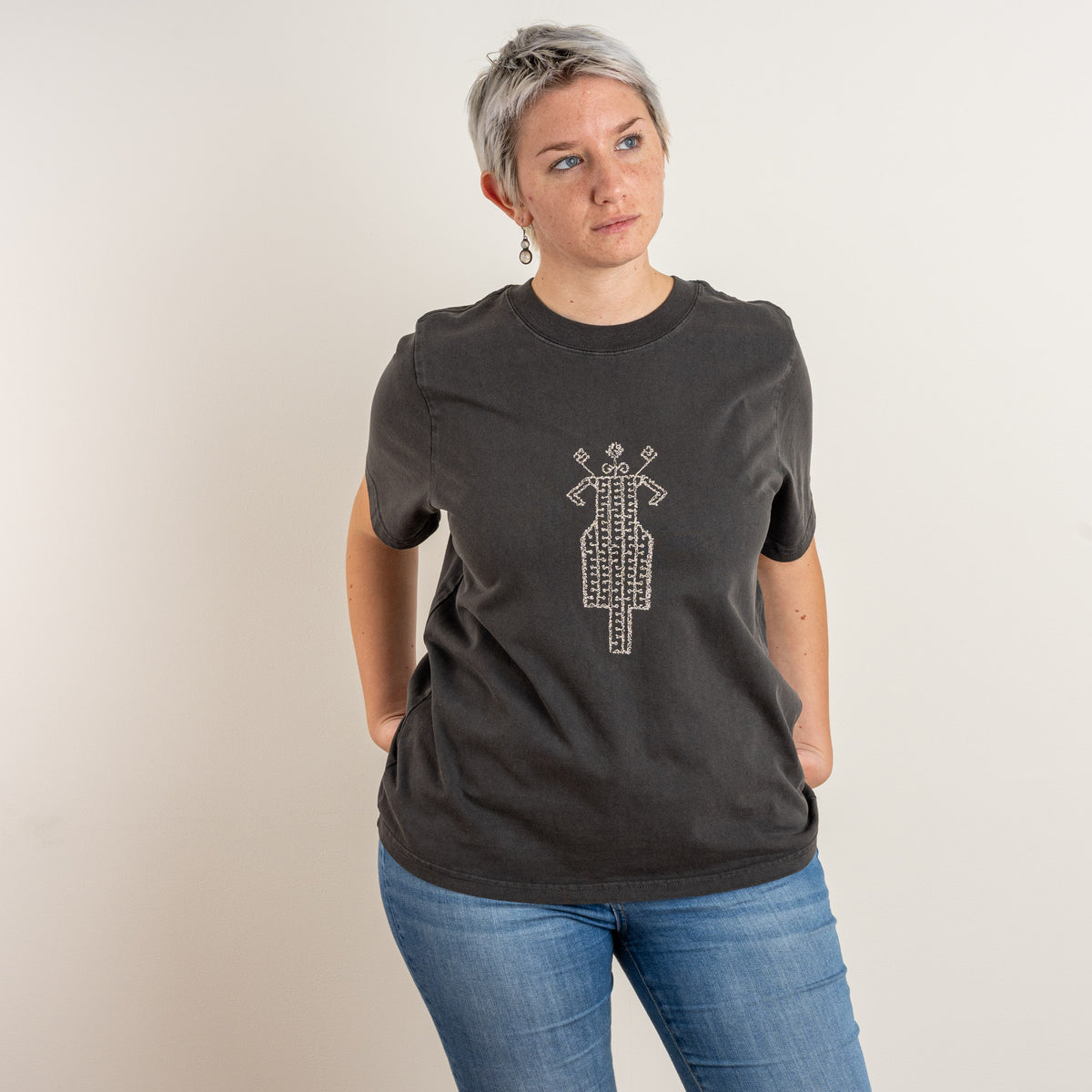 Model in The Ward Faded Black women's T-shirt with the cream embroidered horse-and-rider motif centred on the chest, photographed in Nuenen, Netherlands.