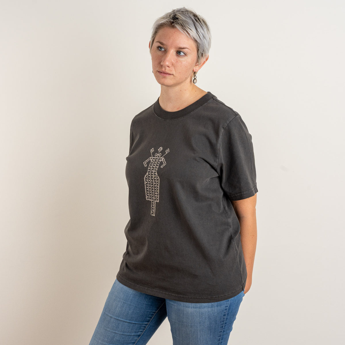 Three-quarter side view of The Ward Faded Black women's T-shirt, showing the garment-dyed 240 GSM cotton and cream folk embroidery.