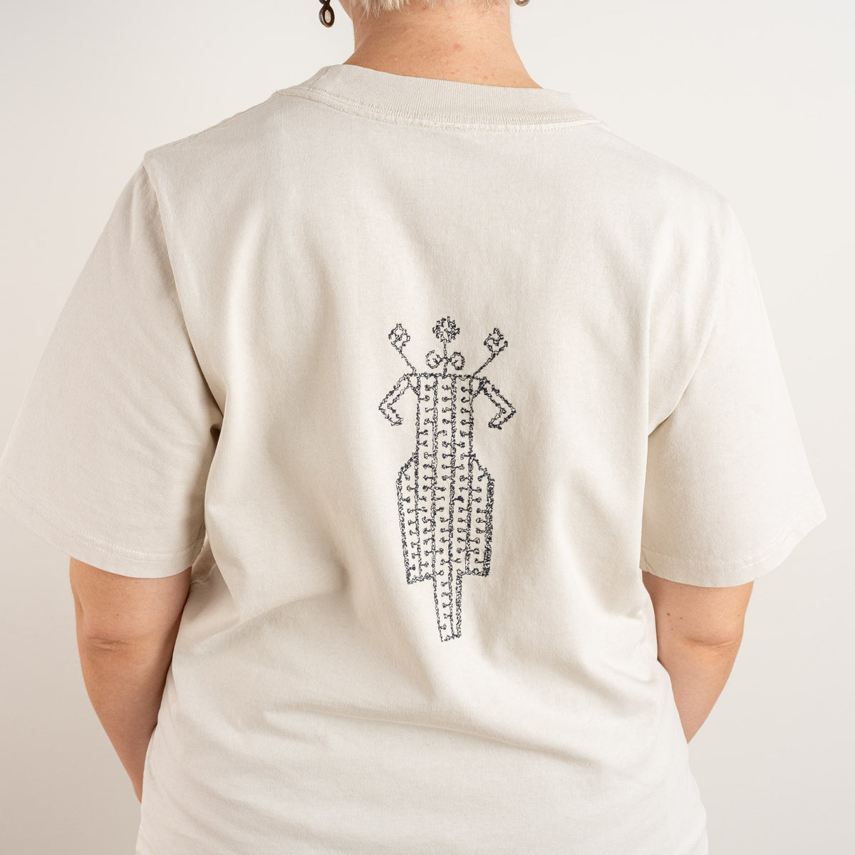 Detailed back view showing the horse-and-rider folk embroidery on The Ward Faded Bone women's T-shirt.