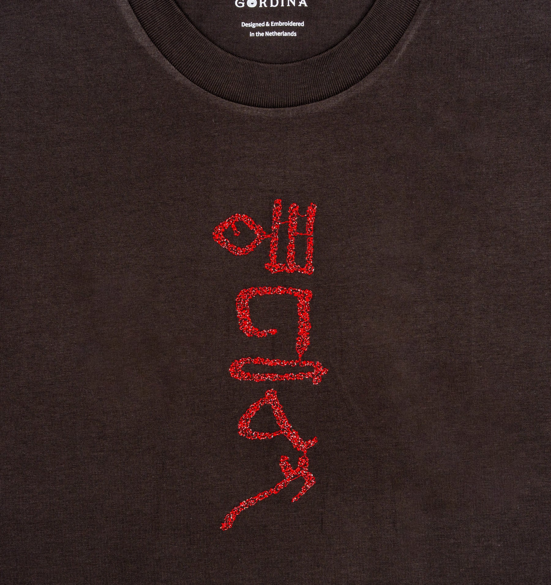 Close-up of hieroglyphic-style embroidery on The Papyrus coal T-shirt