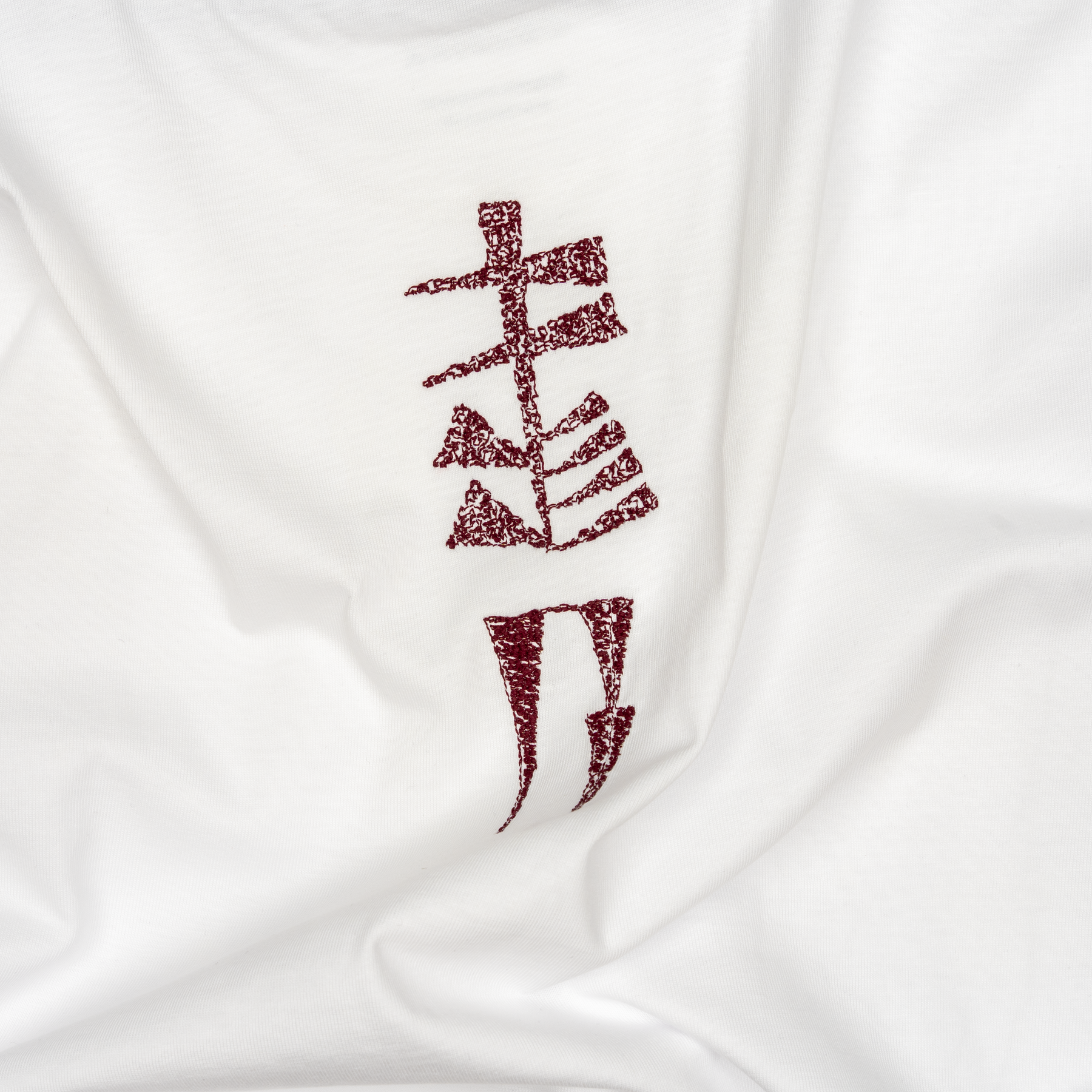 Close-up of the burgundy garden-sign embroidery on the Water and Garden T-shirt