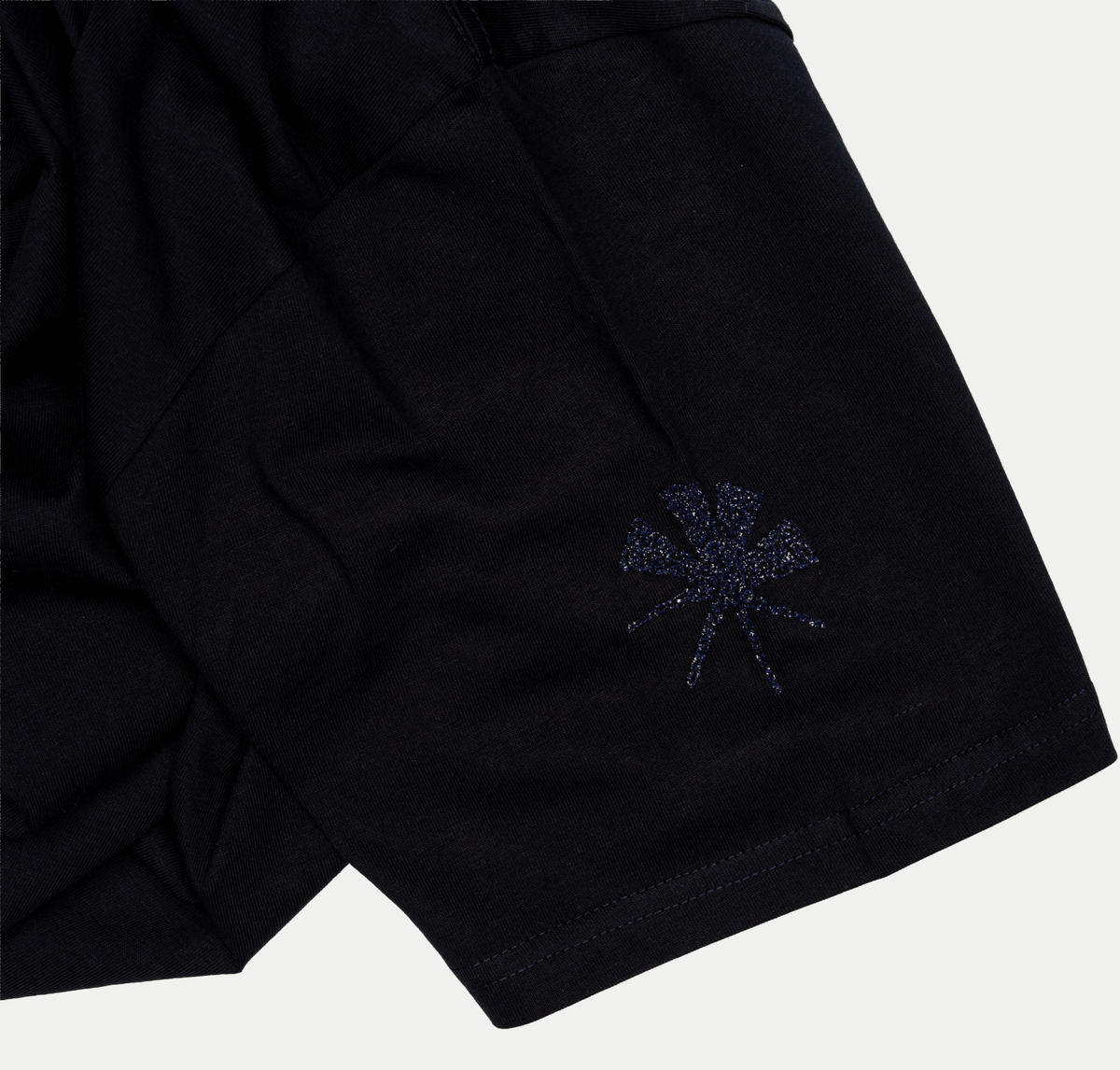 Close-up of the embroidered star on the sleeve of the navy T-shirt.