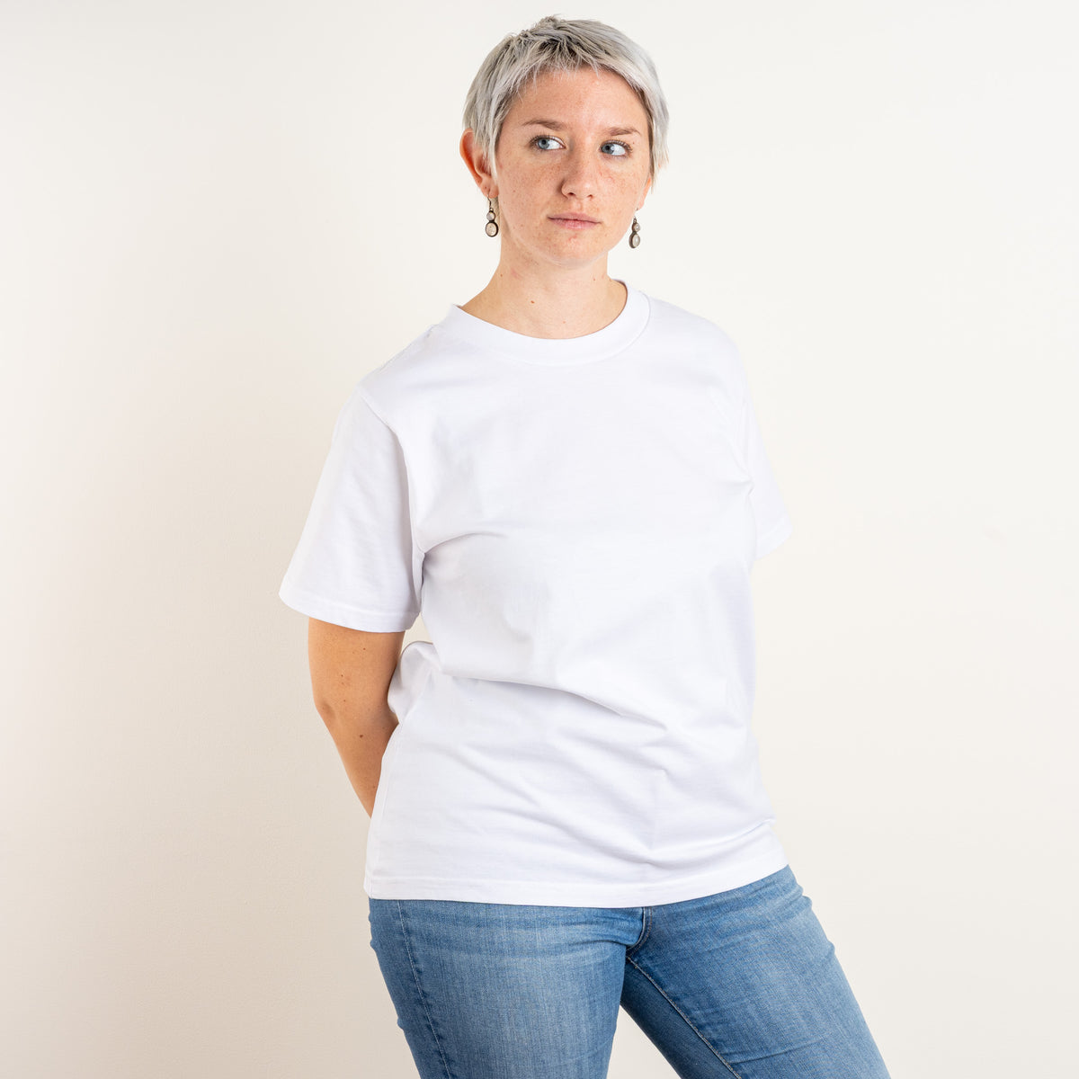Woman wearing Gordina’s white women’s cotton T-shirt, front view; the Water and Garden embroidery is placed on the back. Embroidered in Nuenen, Netherlands.